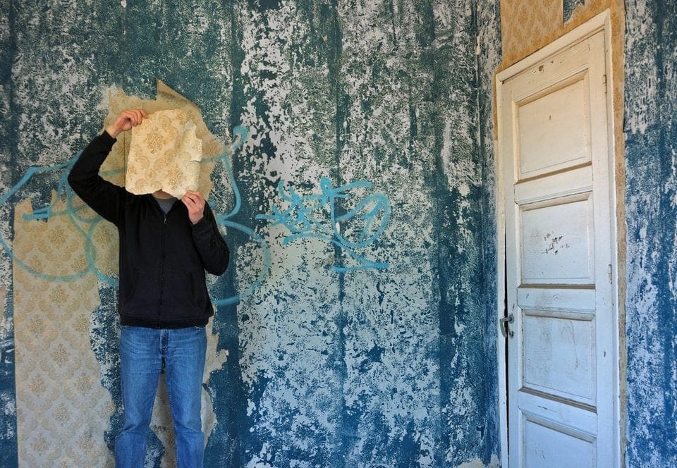 man with torn wallpaper